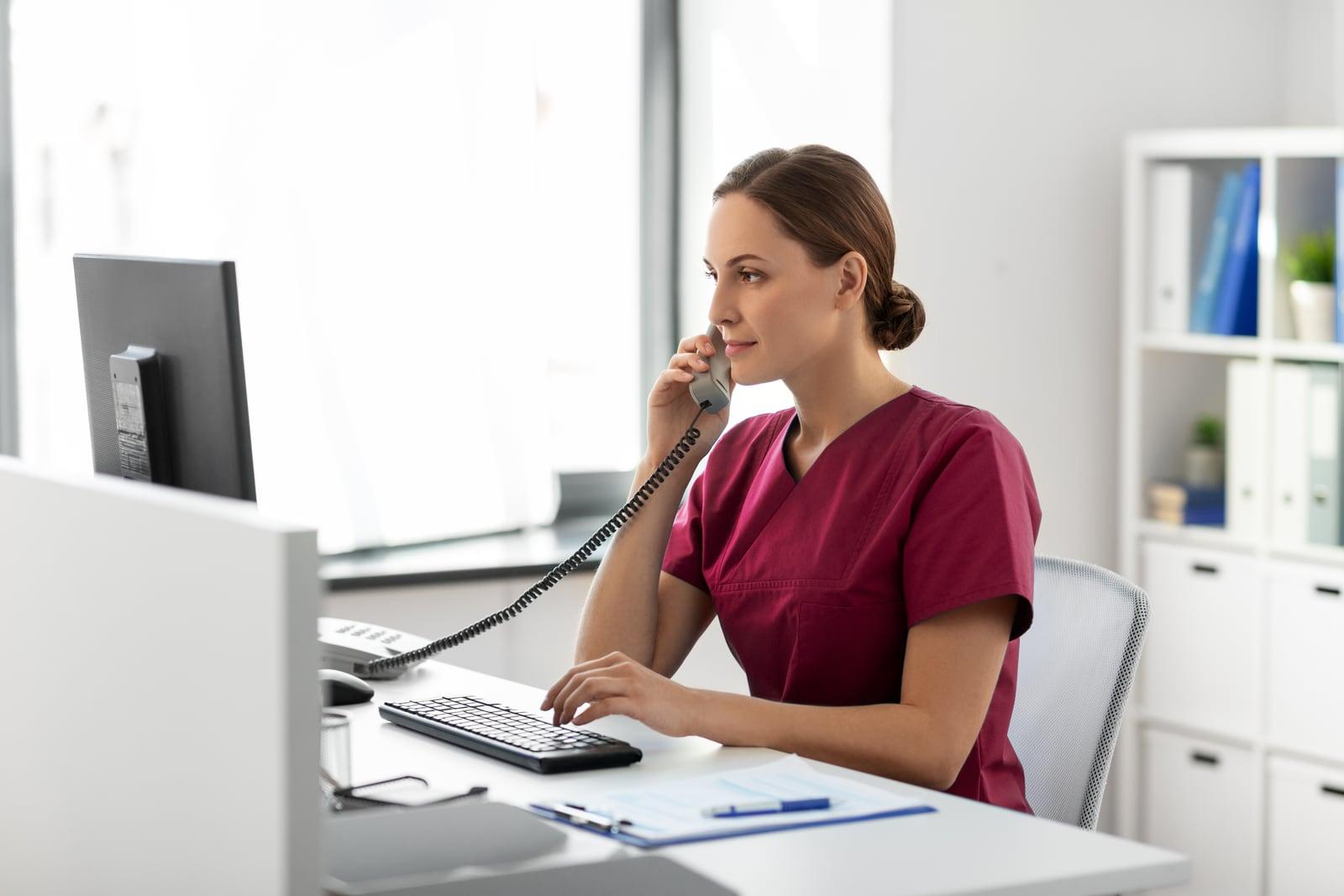 An admissions nurse taking a referral call at her desk