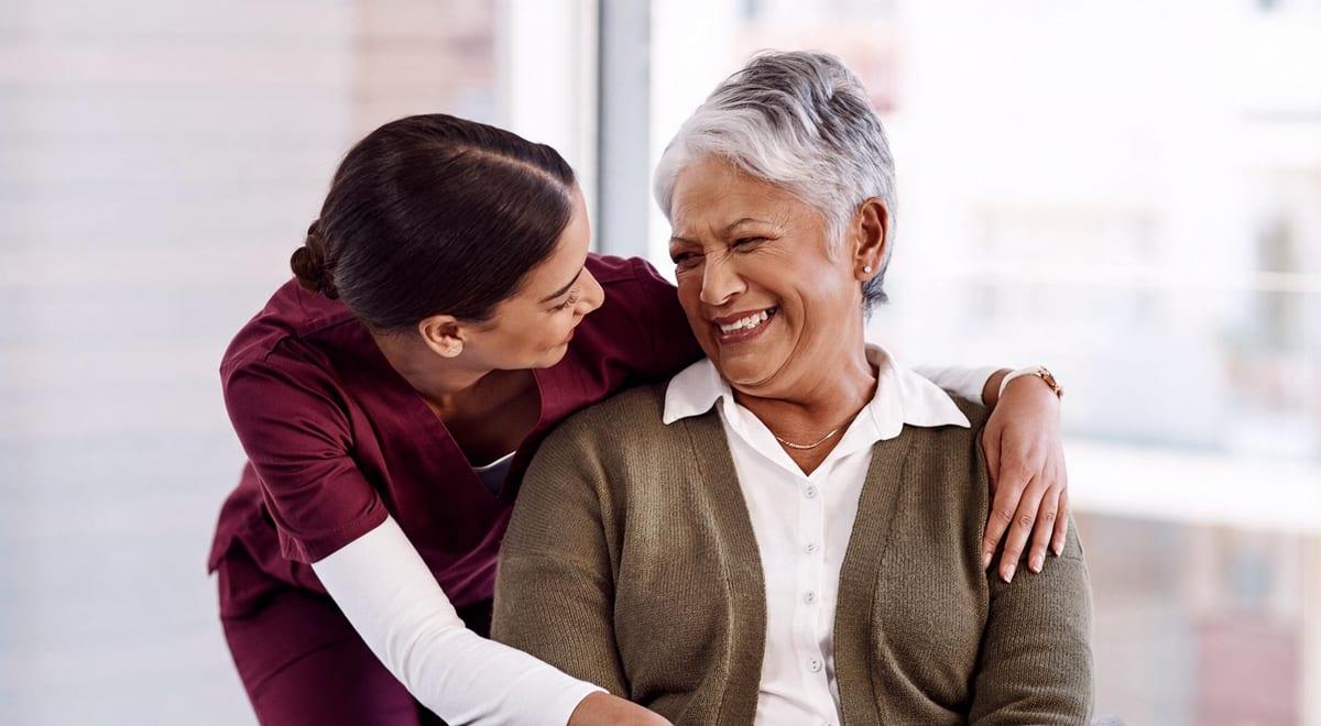 A caregiver hugging a smiling older woman
