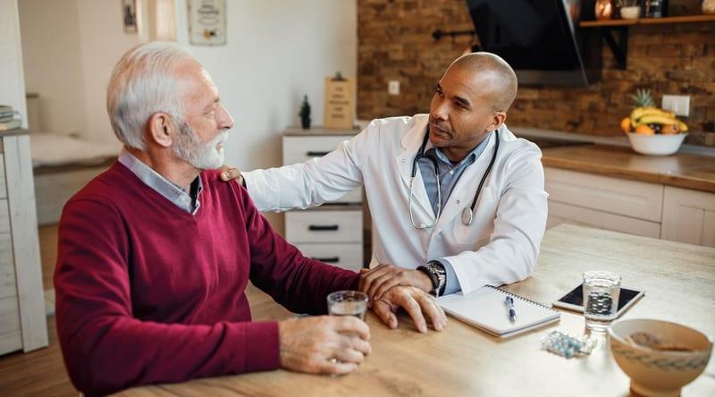A physician talking with an older adult patient at a table