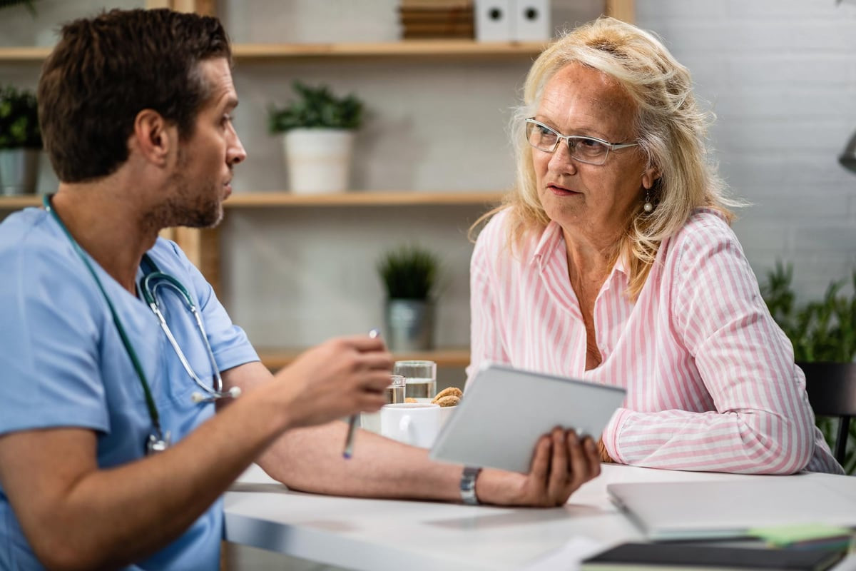 A nurse reviewing a tablet with an older woman
