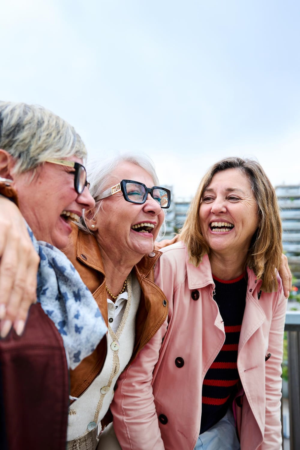 Three older women laughing together outdoors