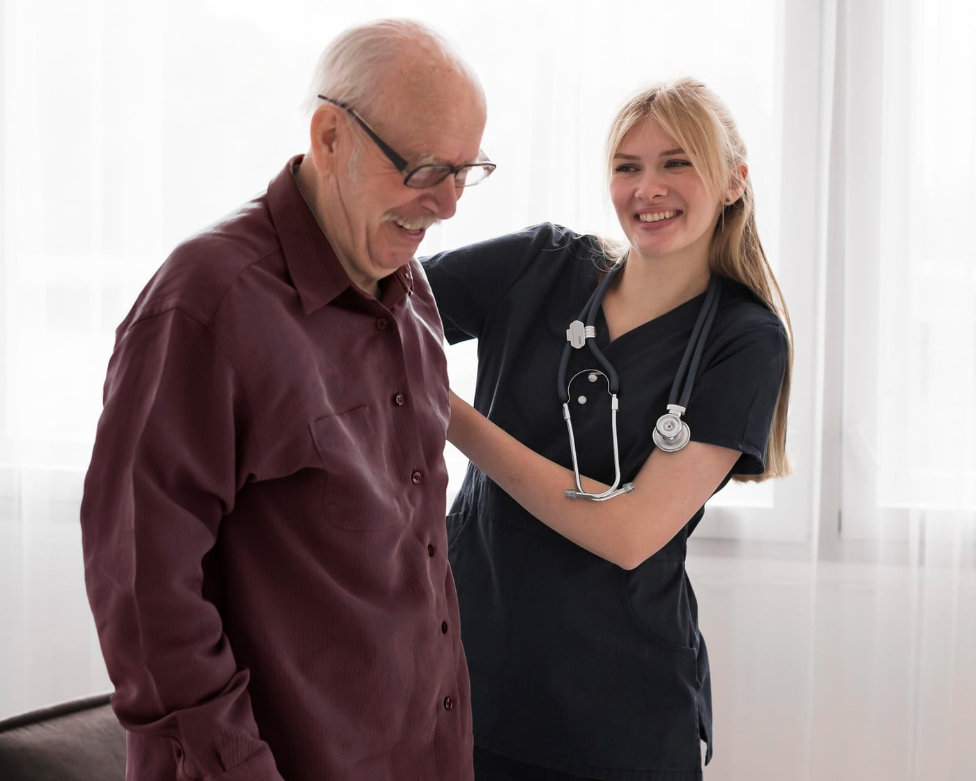 A nurse supporting an older man as he walks